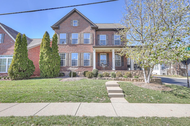 view of front facade featuring a porch, a front yard, and brick siding