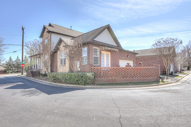 view of side of property with a shingled roof and brick siding