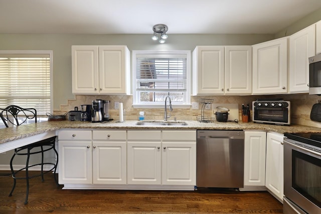 kitchen featuring stainless steel appliances, white cabinetry, a sink, and backsplash