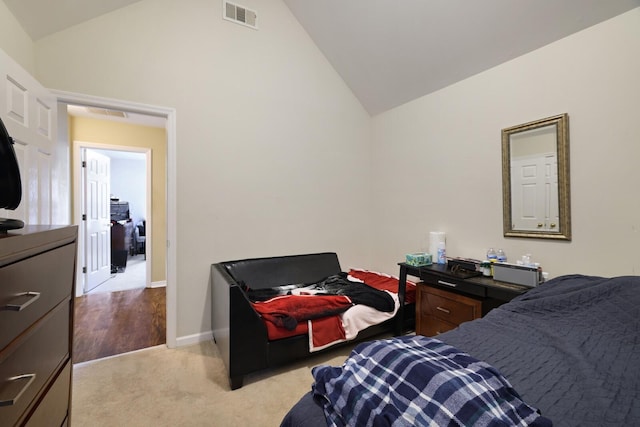 bedroom with light colored carpet, lofted ceiling, visible vents, and baseboards