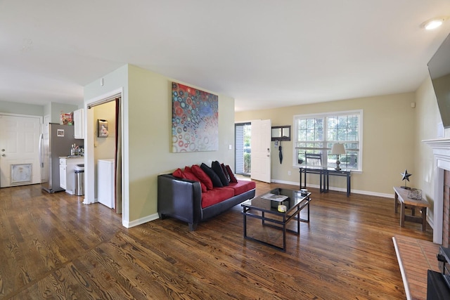 living room featuring dark wood-type flooring, a fireplace, and baseboards