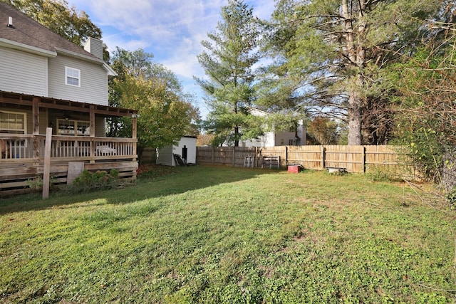 view of yard with a storage shed, fence, a deck, and an outbuilding