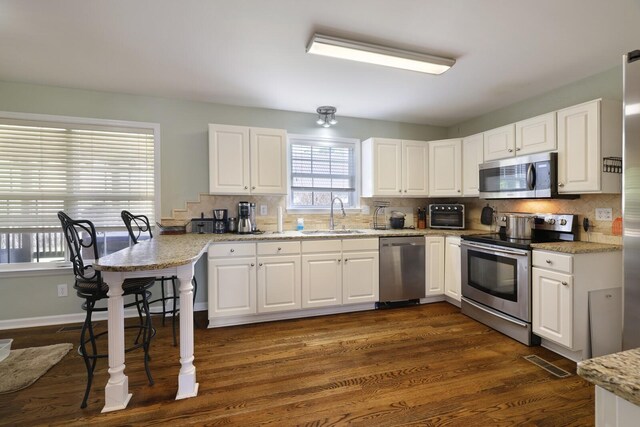 kitchen with visible vents, decorative backsplash, appliances with stainless steel finishes, white cabinetry, and a sink