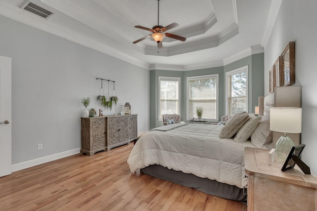 bedroom with visible vents, baseboards, light wood-type flooring, a tray ceiling, and crown molding