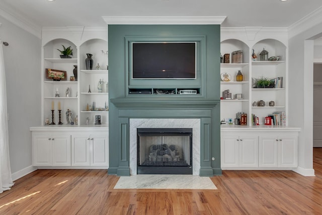 unfurnished living room with light wood-style flooring, built in features, crown molding, and a high end fireplace