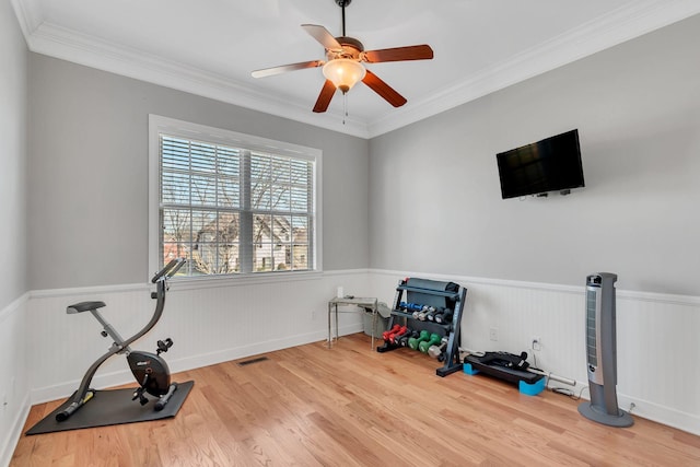 exercise room featuring a wainscoted wall, wood finished floors, visible vents, and crown molding