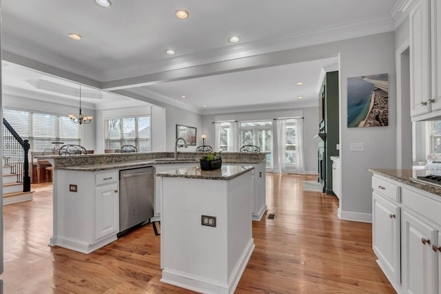 kitchen featuring plenty of natural light, light wood-type flooring, dishwasher, and an island with sink