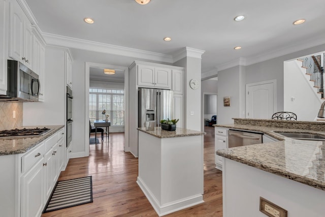 kitchen featuring light wood-style flooring, a kitchen island, stainless steel appliances, and a sink