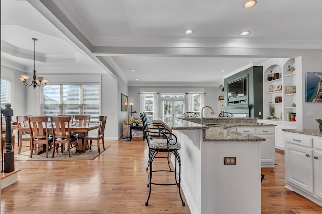 kitchen with a wealth of natural light, light wood finished floors, a sink, and a breakfast bar