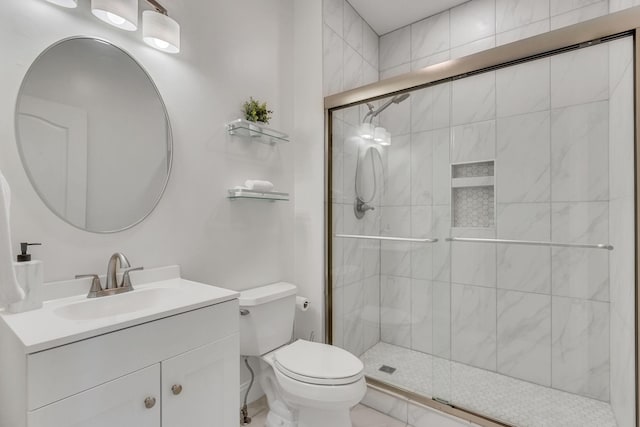 bathroom with toilet, a shower stall, and vanity