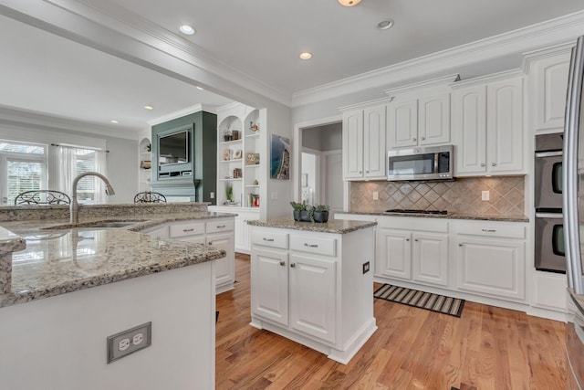 kitchen with light wood-style floors, a kitchen island, stainless steel appliances, and a sink