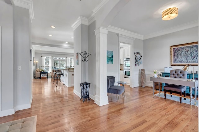 office featuring decorative columns, arched walkways, light wood-style flooring, and crown molding