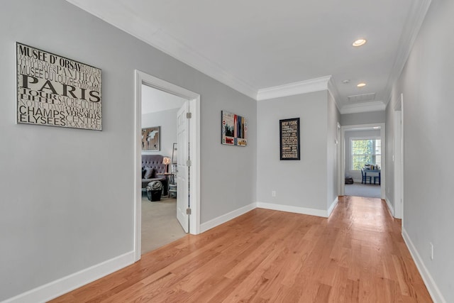 hallway featuring light wood-style floors, baseboards, crown molding, and recessed lighting