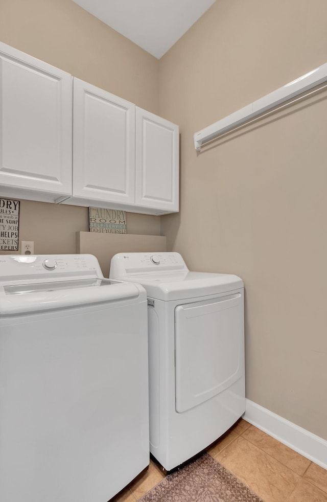 laundry room with cabinet space, light tile patterned floors, baseboards, and washing machine and clothes dryer