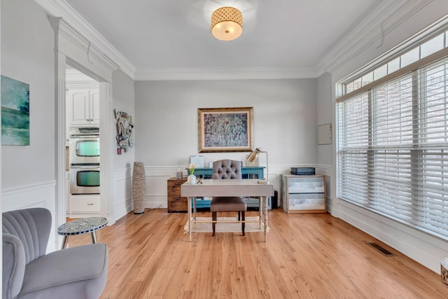 home office featuring wainscoting, visible vents, crown molding, and light wood finished floors