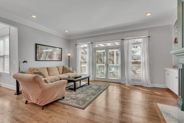 living area with ornamental molding, light wood-style flooring, and baseboards