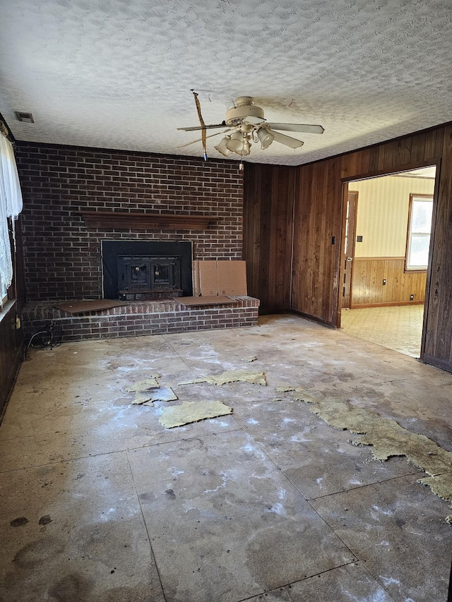 unfurnished living room featuring a textured ceiling, wood walls, and visible vents