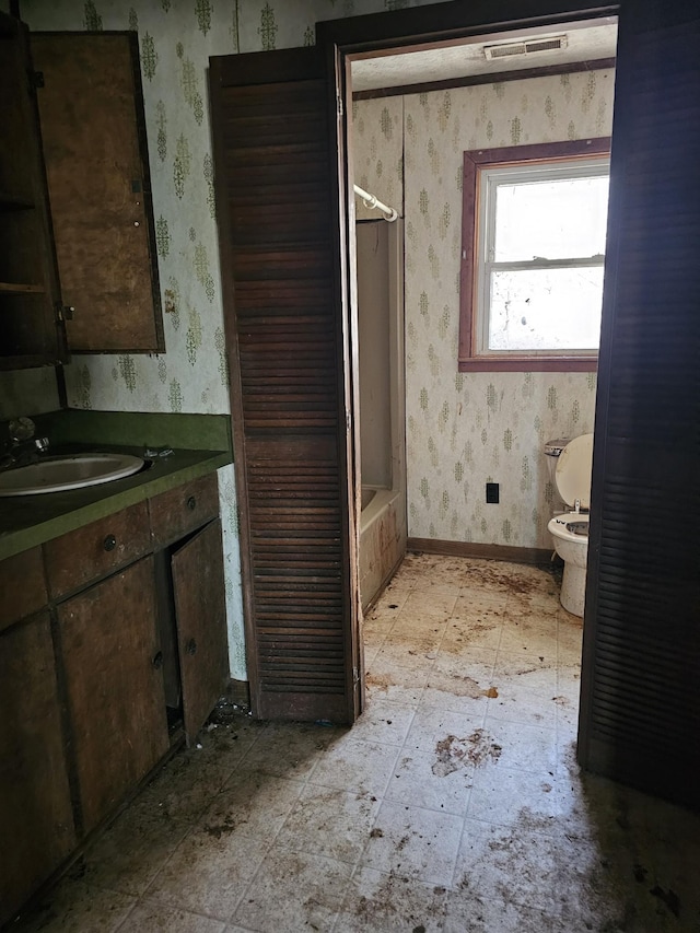 bathroom with wallpapered walls, visible vents, baseboards, toilet, and vanity