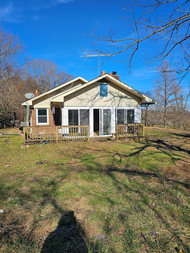 view of front of house with brick siding, a chimney, a front lawn, and a wooden deck