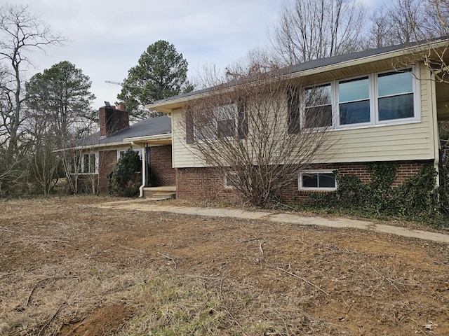 view of front facade with brick siding and a chimney