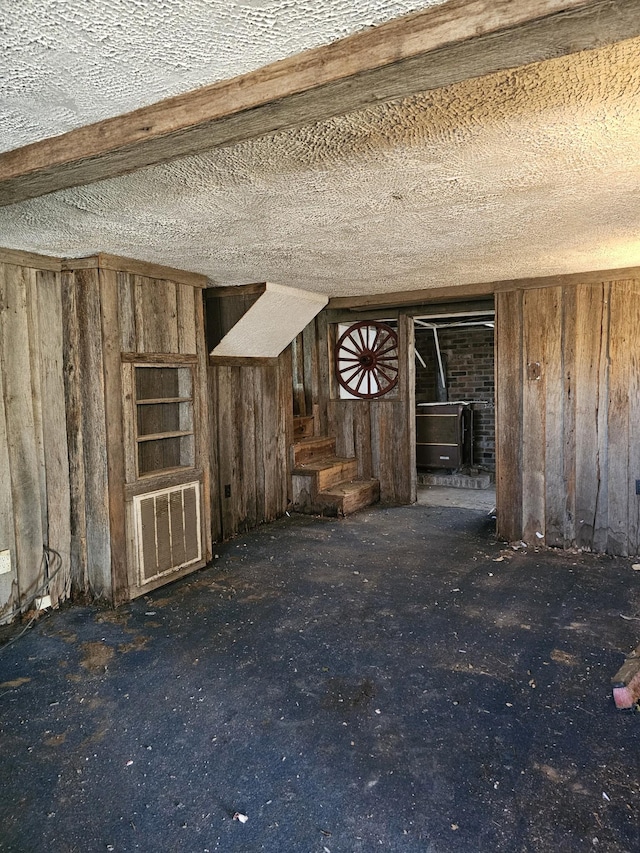 unfurnished living room with wooden walls and a textured ceiling