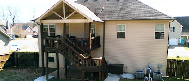 rear view of house with a shingled roof, fence, stairway, and central air condition unit