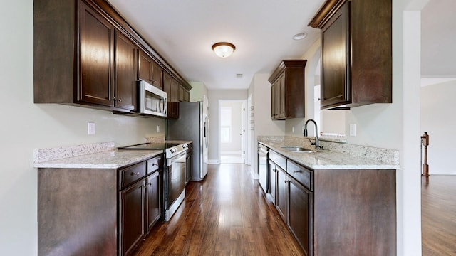 kitchen with dark brown cabinets, appliances with stainless steel finishes, dark wood-type flooring, and a sink