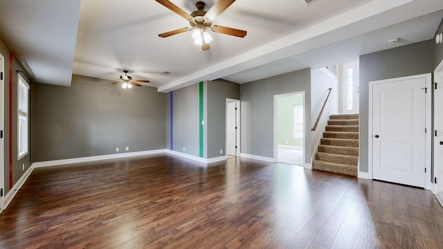 spare room featuring wood finished floors, ceiling fan, baseboards, and stairs