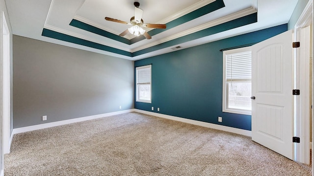 spare room featuring baseboards, visible vents, a raised ceiling, crown molding, and carpet flooring