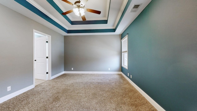 carpeted spare room with crown molding, a raised ceiling, visible vents, and baseboards