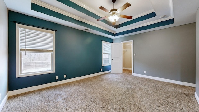 unfurnished room with carpet flooring, a raised ceiling, and crown molding