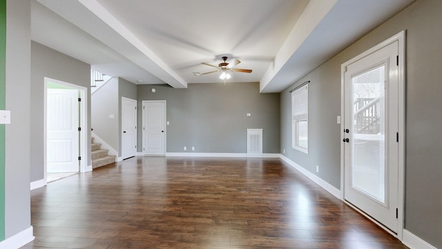 unfurnished living room featuring baseboards, a ceiling fan, stairway, dark wood-type flooring, and beamed ceiling