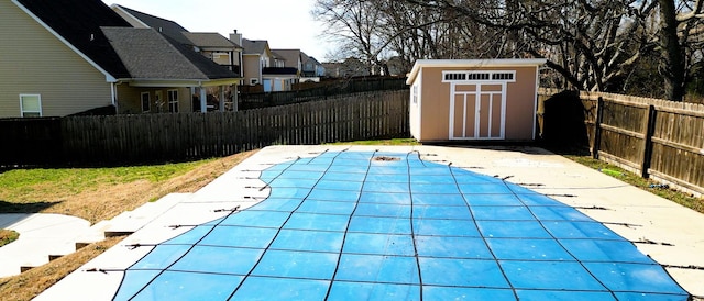 view of pool featuring a fenced in pool, a fenced backyard, a residential view, an outdoor structure, and a shed