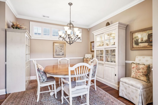 dining room featuring dark wood-style flooring, an inviting chandelier, visible vents, and crown molding