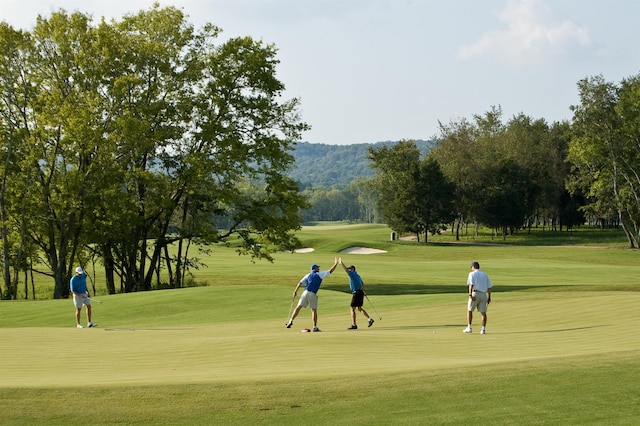 view of home's community featuring view of golf course and a lawn