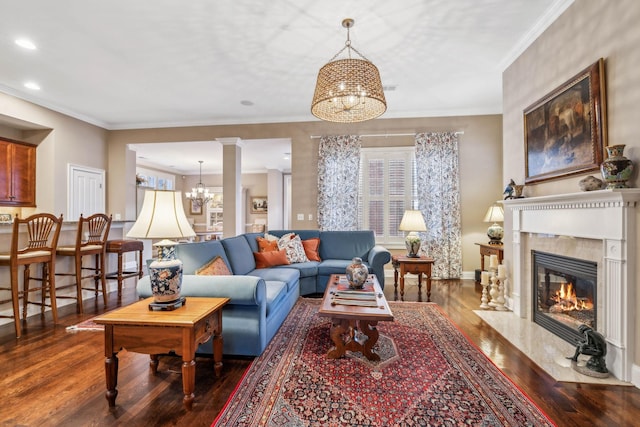 living room featuring a chandelier, a fireplace, wood finished floors, baseboards, and crown molding