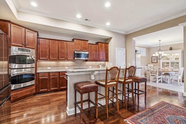 kitchen with tasteful backsplash, appliances with stainless steel finishes, a breakfast bar, dark wood-style flooring, and light stone countertops