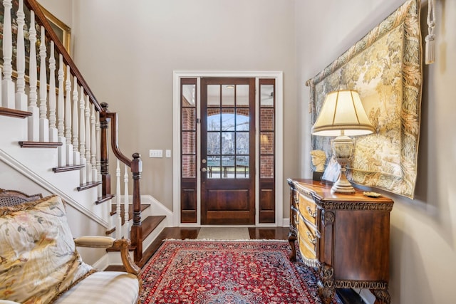 foyer with stairway, baseboards, and wood finished floors