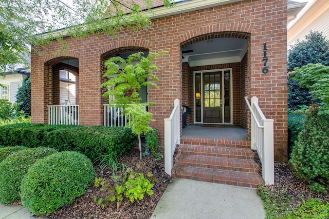 view of exterior entry featuring a porch and brick siding