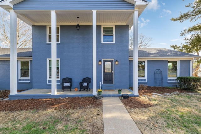 view of front of property featuring brick siding, a porch, and a shingled roof