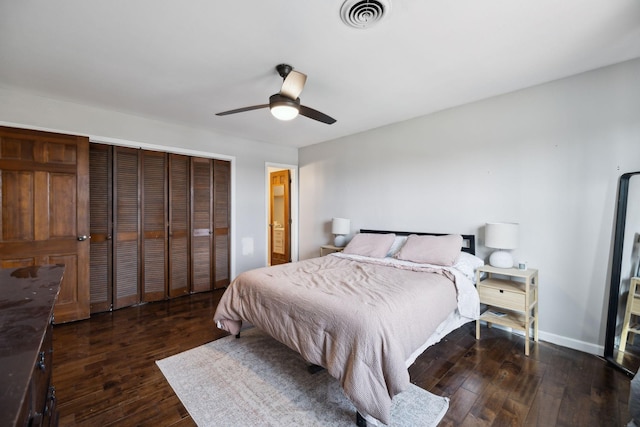 bedroom with visible vents, dark wood-type flooring, ceiling fan, baseboards, and a closet