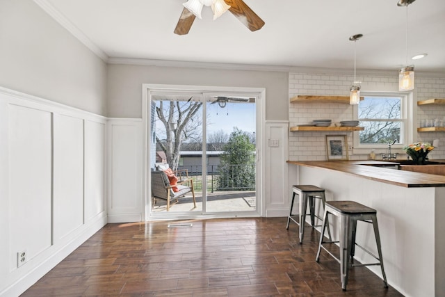 kitchen with dark wood finished floors, butcher block counters, a breakfast bar, and open shelves