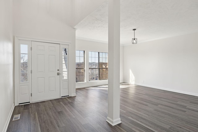 foyer featuring dark wood-style flooring, crown molding, visible vents, a textured ceiling, and baseboards