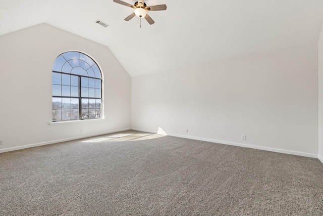 carpeted spare room featuring lofted ceiling, visible vents, baseboards, and a ceiling fan