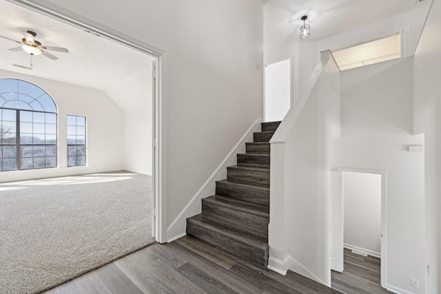 stairs featuring lofted ceiling, ceiling fan, carpet floors, wood finished floors, and baseboards