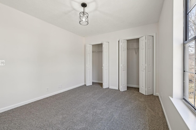 unfurnished bedroom featuring carpet, two closets, and baseboards