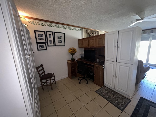 home office with light tile patterned floors, ceiling fan, and a textured ceiling