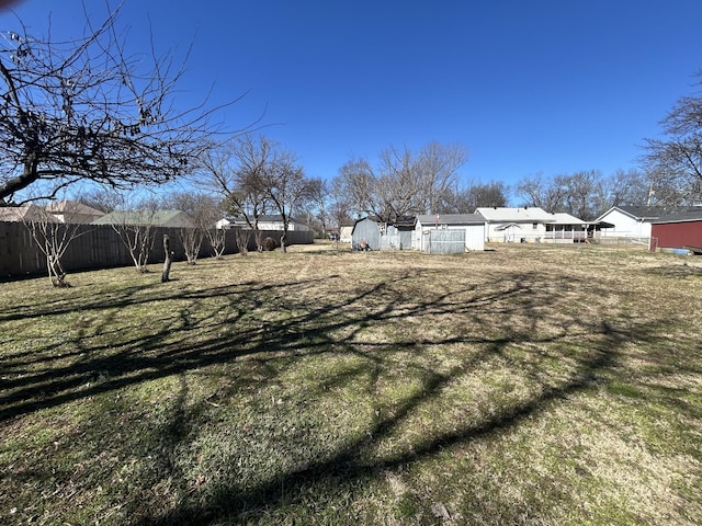 view of yard featuring an outbuilding, a fenced backyard, and a storage unit