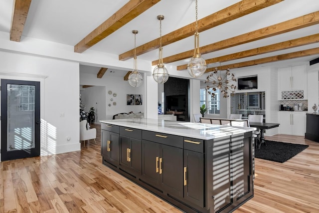 kitchen with dark cabinets, open floor plan, light wood-style floors, and backsplash