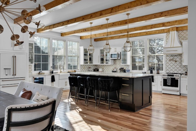 kitchen with premium appliances, a kitchen island, white cabinets, a kitchen bar, and glass insert cabinets